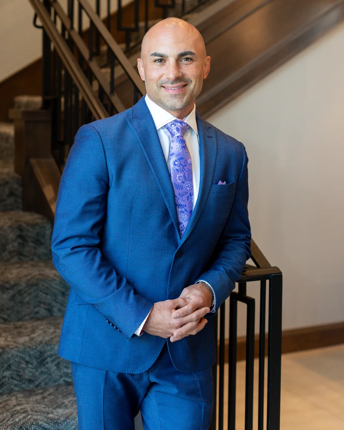 Dr. Castel Santana standing on a staircase in a blue suit