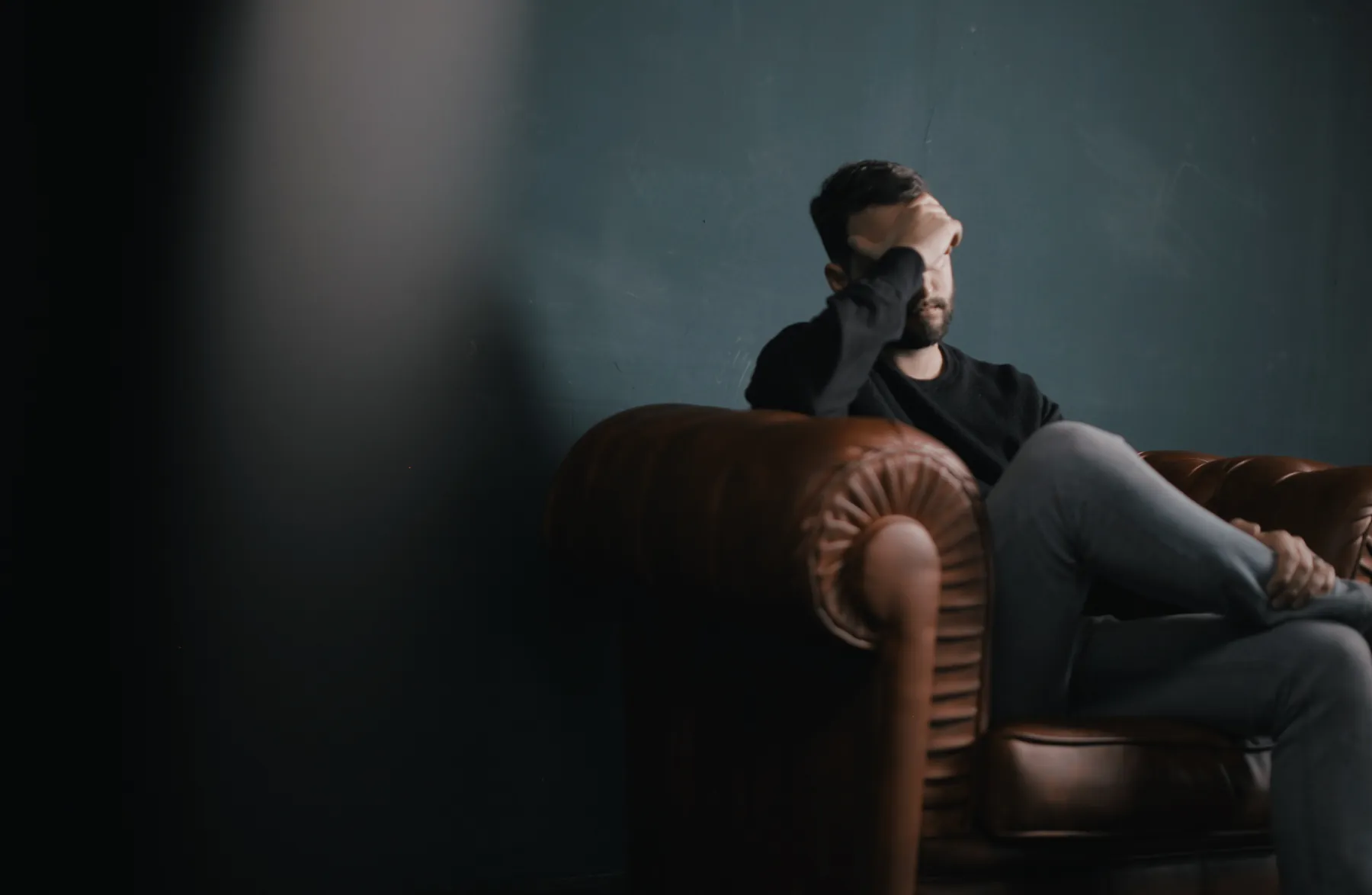 A tired man in a leather armchair, rubbing his eyes