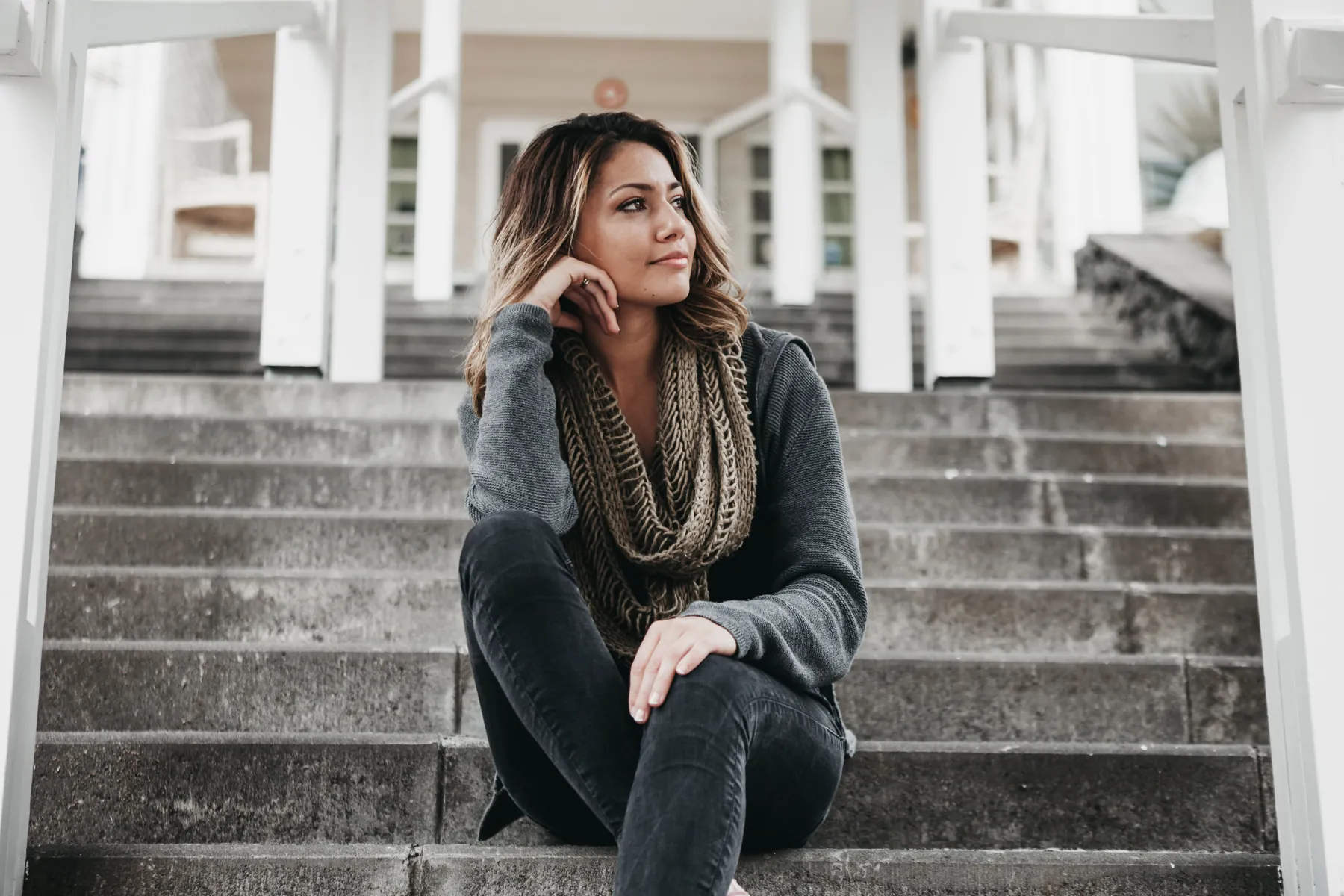 A woman sitting on outdoor steps, chin in hand, deep in thought
