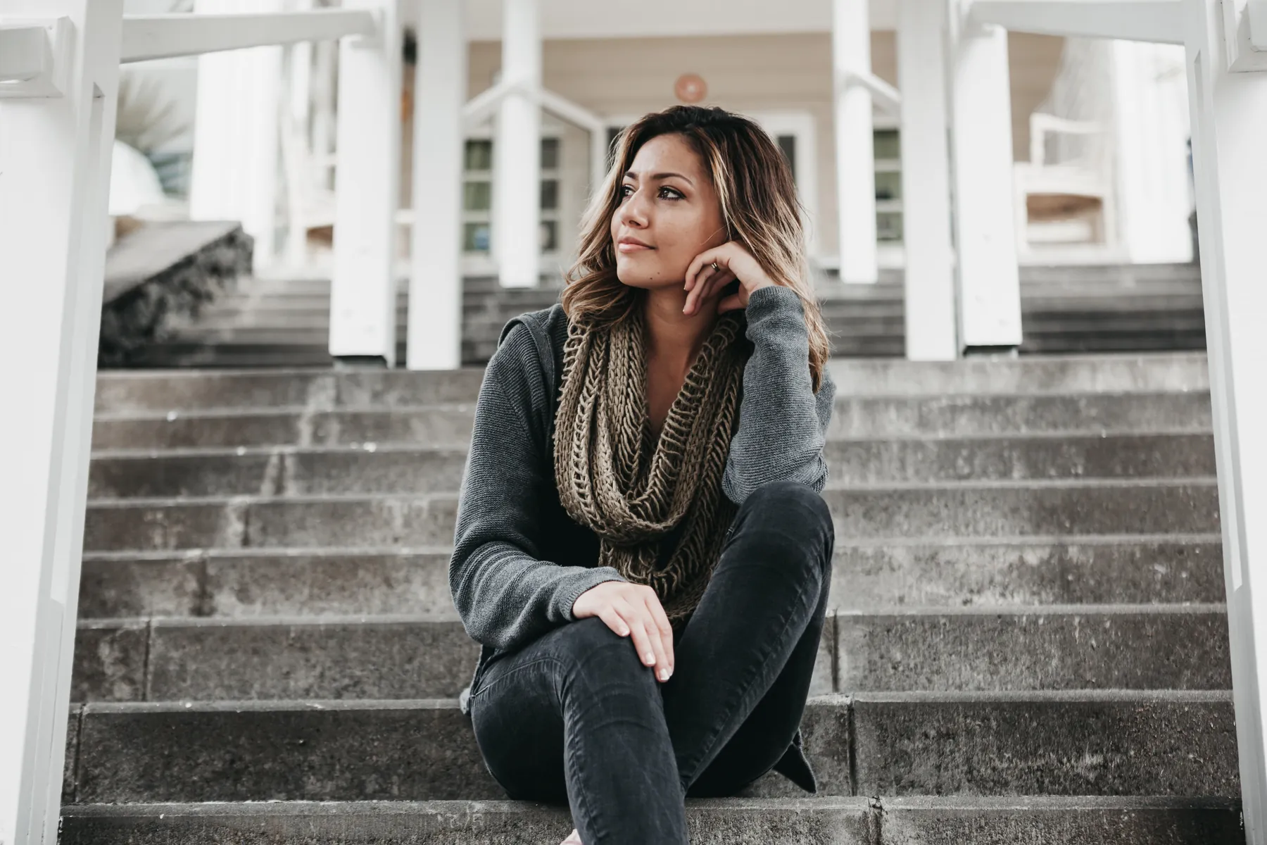 A woman sitting on outdoor steps, chin in hand, deep in thought